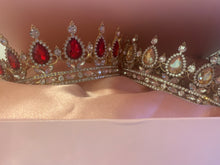 Load image into Gallery viewer, Two diamanté sparkling crowns, one set with oval champagne coloured stones and the other with faux rubies in a pink box with a silky pink lining inside the box and a pink bow to tie and secure the box closed.